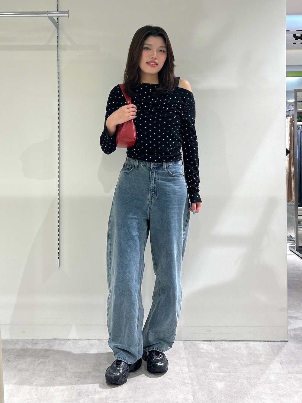 ブルー系のデニムパンツ、レッド系のショルダーバッグ、ブラック系のTシャツ/カットソーを着用したレディースの秋コーディネートの2枚目の写真