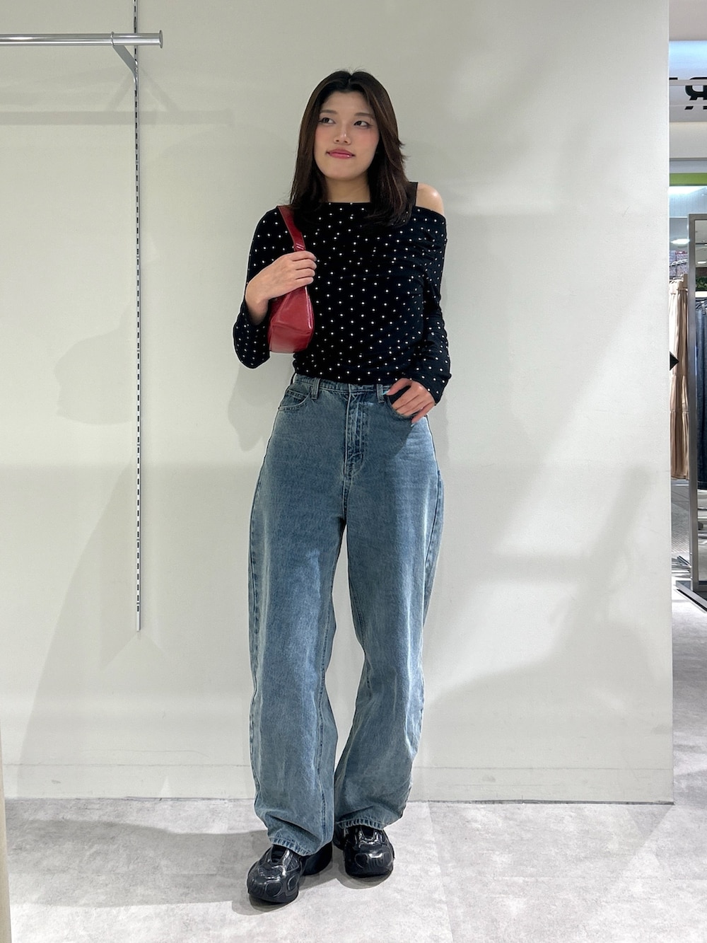 ブルー系のデニムパンツ、レッド系のショルダーバッグ、ブラック系のTシャツ/カットソーを着用したレディースの秋コーディネートの3枚目の写真
