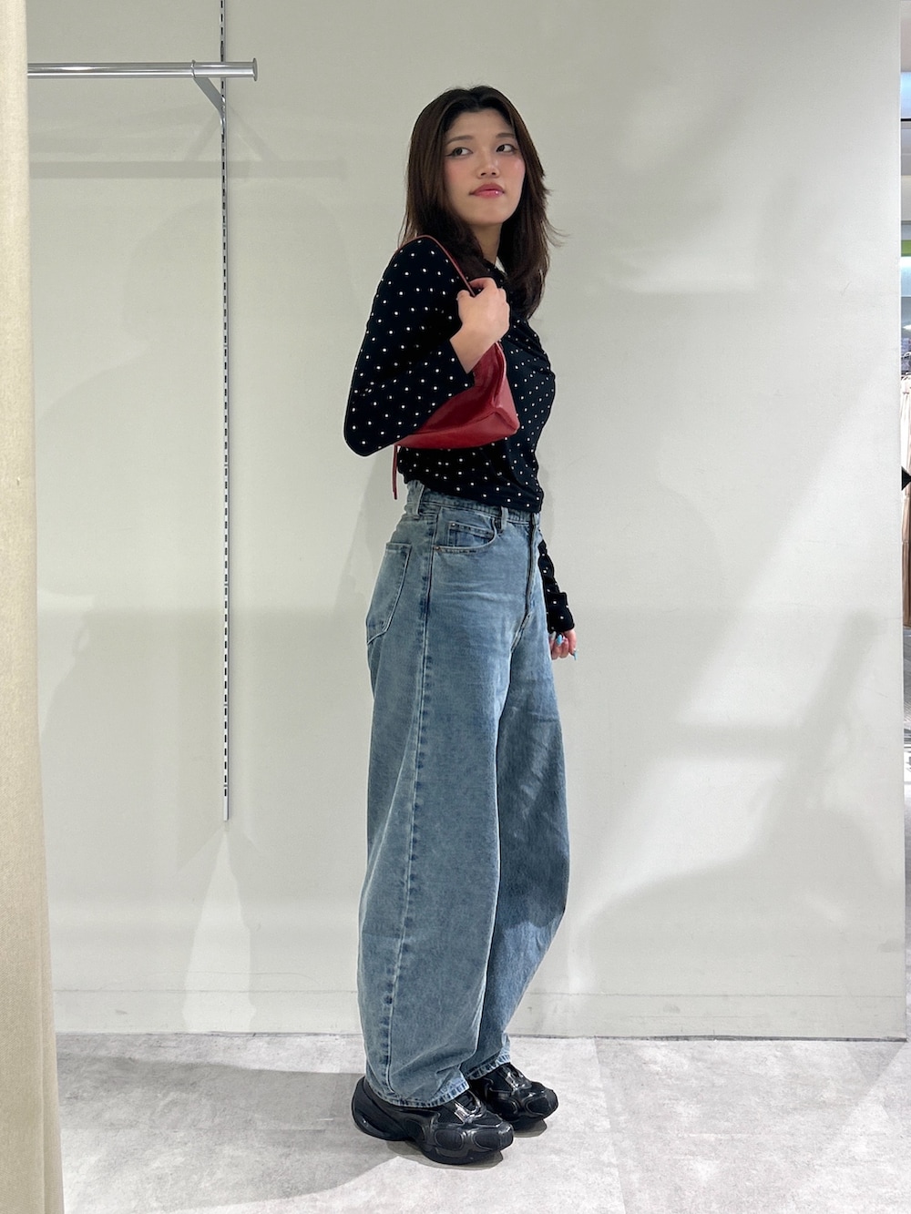 ブルー系のデニムパンツ、レッド系のショルダーバッグ、ブラック系のTシャツ/カットソーを着用したレディースの秋コーディネートの4枚目の写真