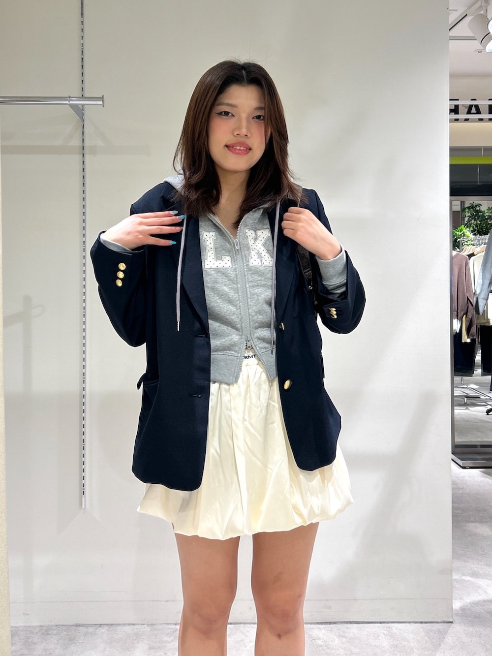 ホワイト系のスカート、ブルー系のテーラードジャケット、グレー系のTシャツ/カットソーを着用したレディースの秋コーディネートの6枚目の写真
