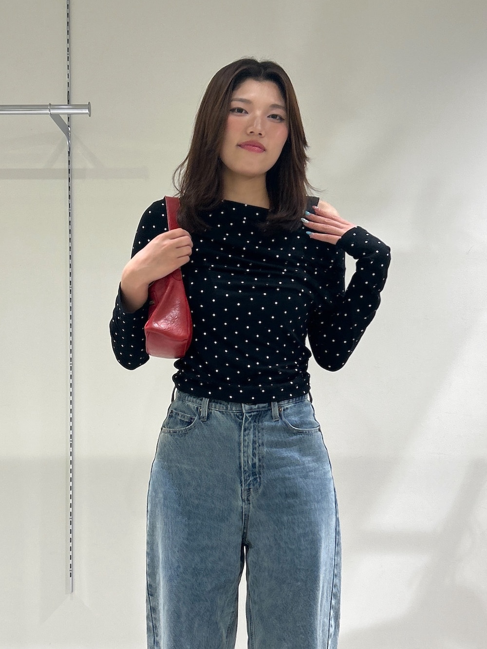 ブルー系のデニムパンツ、レッド系のショルダーバッグ、ブラック系のTシャツ/カットソーを着用したレディースの秋コーディネートの6枚目の写真