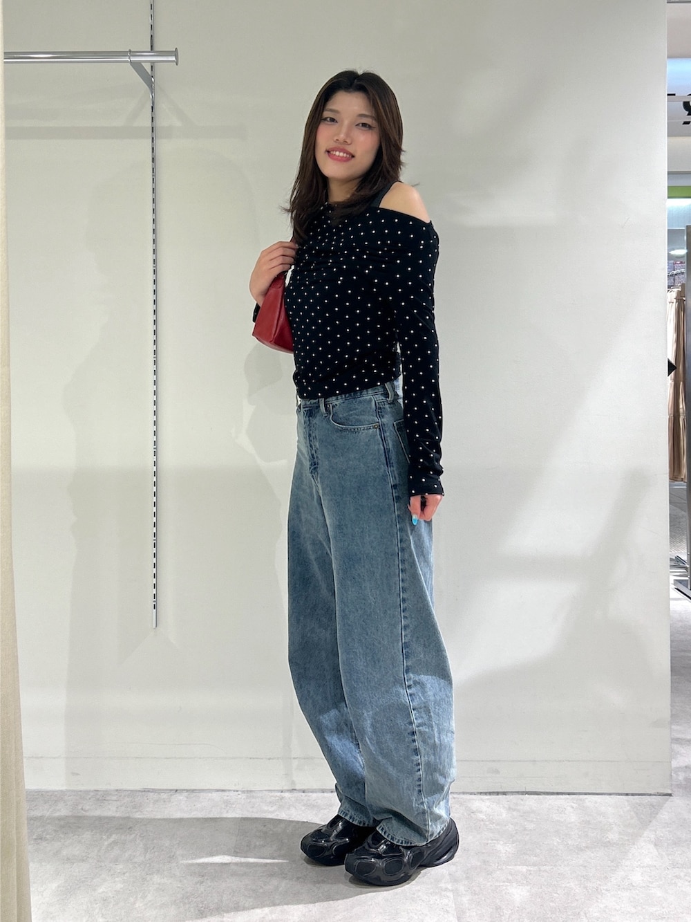 ブルー系のデニムパンツ、レッド系のショルダーバッグ、ブラック系のTシャツ/カットソーを着用したレディースの秋コーディネートの5枚目の写真