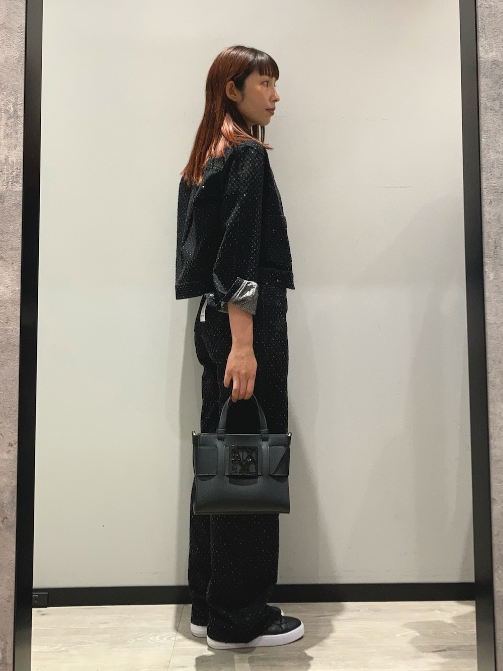 ブラック系のデニムジャケット、ブラック系のハンドバッグ、ブラック系のデニムパンツを着用したレディースの春コーディネートの2枚目の写真