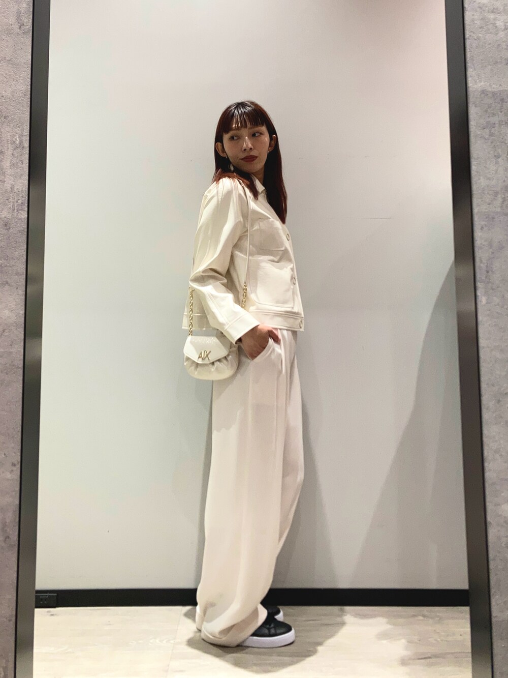 ホワイト系のブルゾン、ホワイト系のスラックス、ホワイト系のショルダーバッグを着用したレディースの冬コーディネートの2枚目の写真