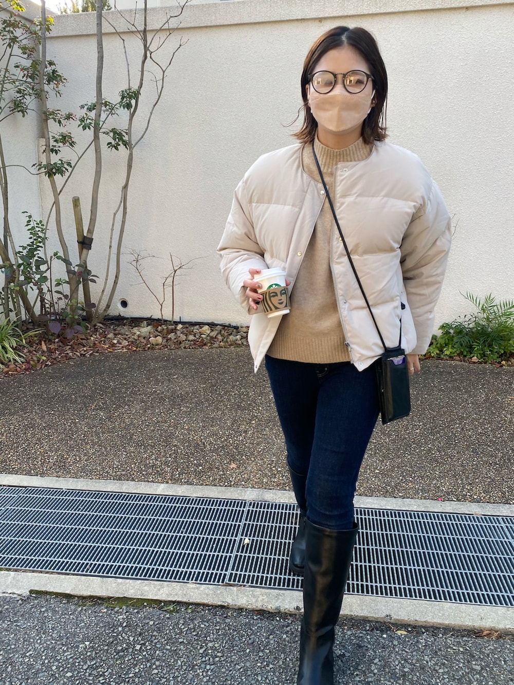 ブルー系のデニムパンツ、ブラック系のシューズ、ベージュ系のダウンジャケット/コートを着用したレディースの冬コーディネートの2枚目の写真