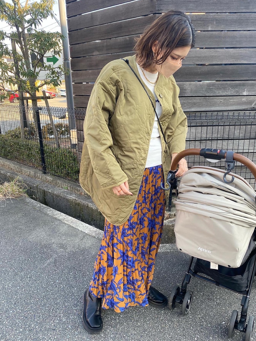 ホワイト系のスウェット、グリーン系のジャケット/アウター、オレンジ系のスカートを着用したレディースの冬コーディネートの2枚目の写真