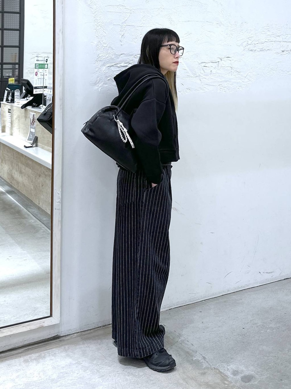 ブラック系のサロペット/オーバーオール、ブラック系のボストンバッグ、ブラック系のパーカーを着用したレディースの冬コーディネートの2枚目の写真