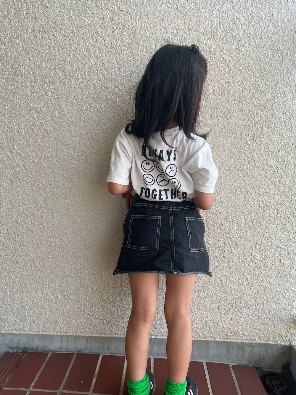 ブラック系のデニムスカート、ホワイト系のTシャツ/カットソー、ブラック系のスニーカーを着用したキッズの夏コーディネートの4枚目の写真