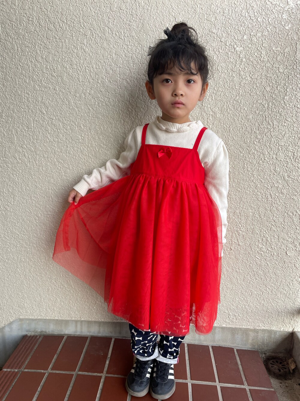 レッド系のチュニック、ブルー系のデニムパンツ、ブラック系のスニーカーを着用したキッズの冬コーディネートの2枚目の写真