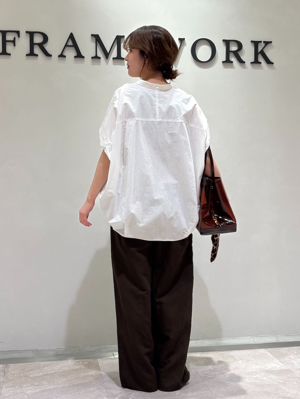 ブラウン系のスラックス、ホワイト系のシャツ/ブラウス、ベージュ系のタンクトップを着用したレディースの春コーディネートの3枚目の写真