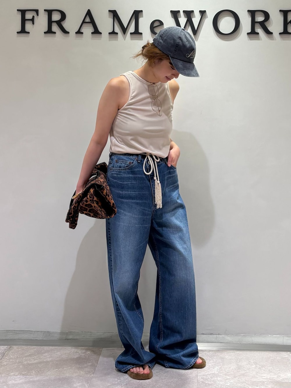 ブルー系のデニムパンツ、イエロー系のトートバッグ、イエロー系のサンダルを着用したレディースの夏コーディネートの5枚目の写真