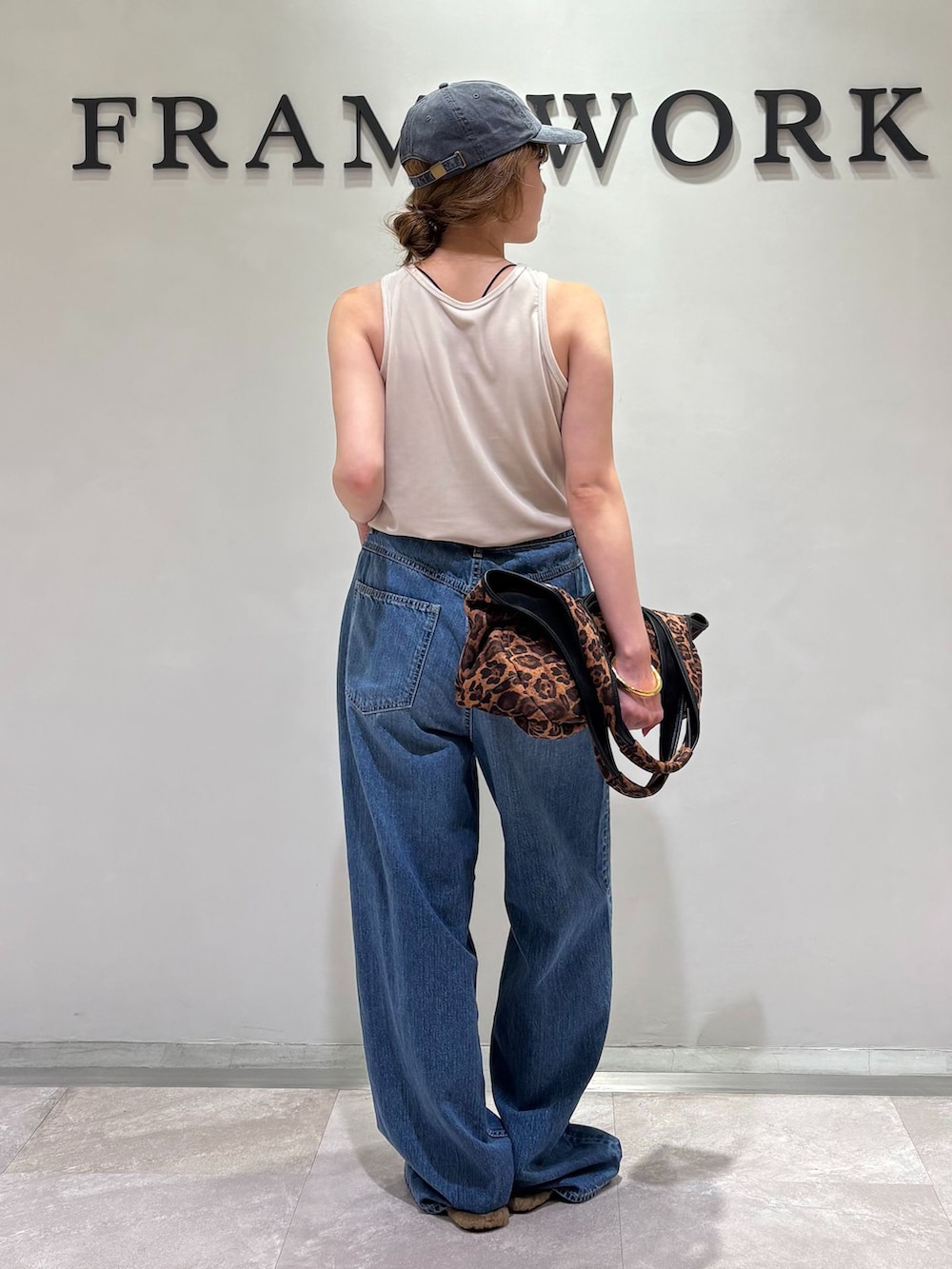 ブルー系のデニムパンツ、イエロー系のトートバッグ、イエロー系のサンダルを着用したレディースの夏コーディネートの3枚目の写真