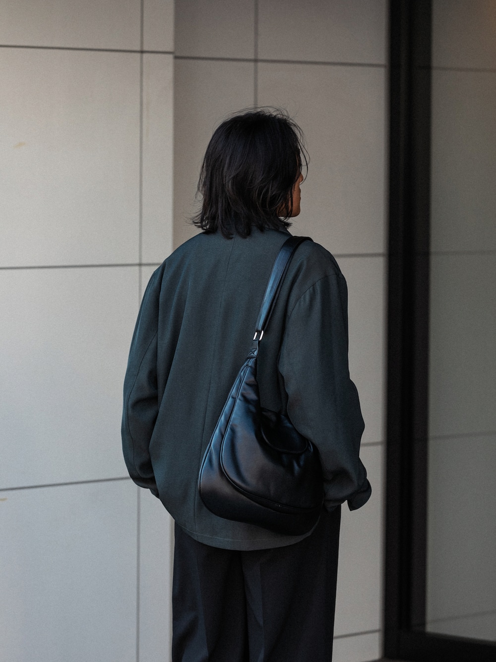 ブラック系のニット/セーター、ブラック系のスラックス、グレー系のその他アウターを着用したメンズの秋コーディネートの5枚目の写真