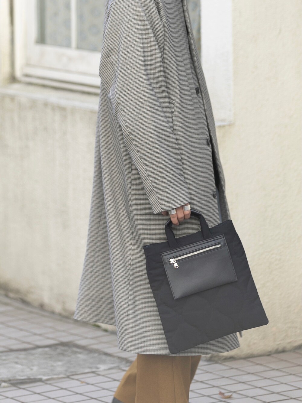 ブラック系のトートバッグ、ベージュ系のステンカラーコート、ブラック系のスニーカーを着用したメンズの冬コーディネートの4枚目の写真