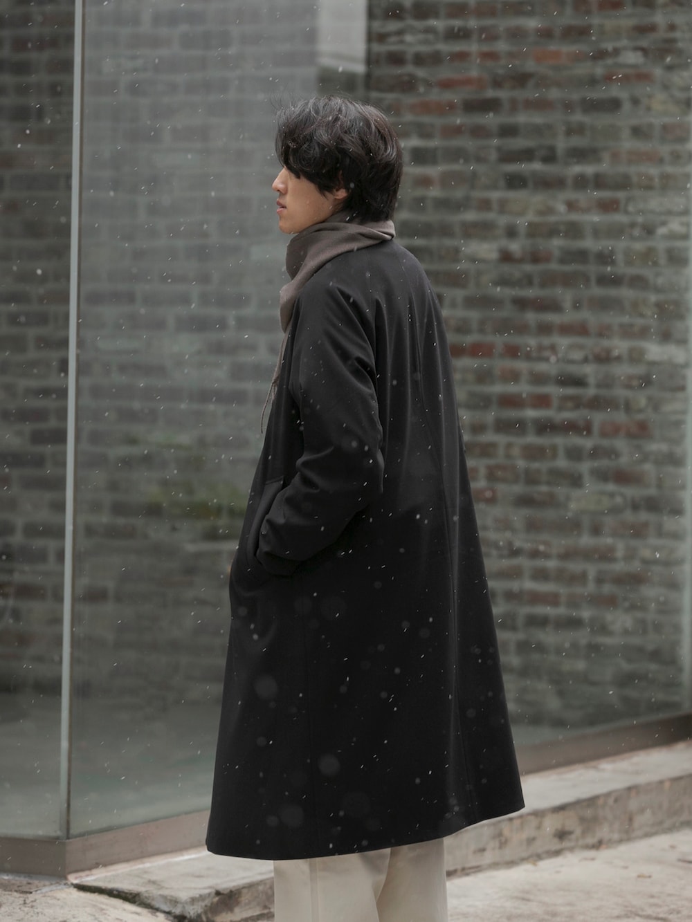 ブラック系のステンカラーコート、ホワイト系のチノパンツ、ブラック系のドレスシューズを着用したメンズの冬コーディネートの2枚目の写真