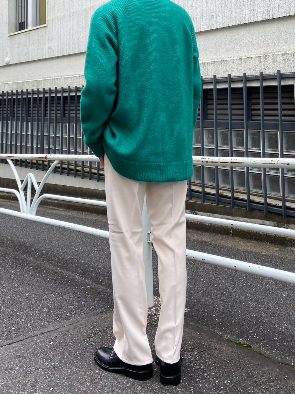 ベージュ系のスラックス、ブラック系のドレスシューズ、グリーン系のニット/セーターを着用したメンズの秋コーディネートの3枚目の写真