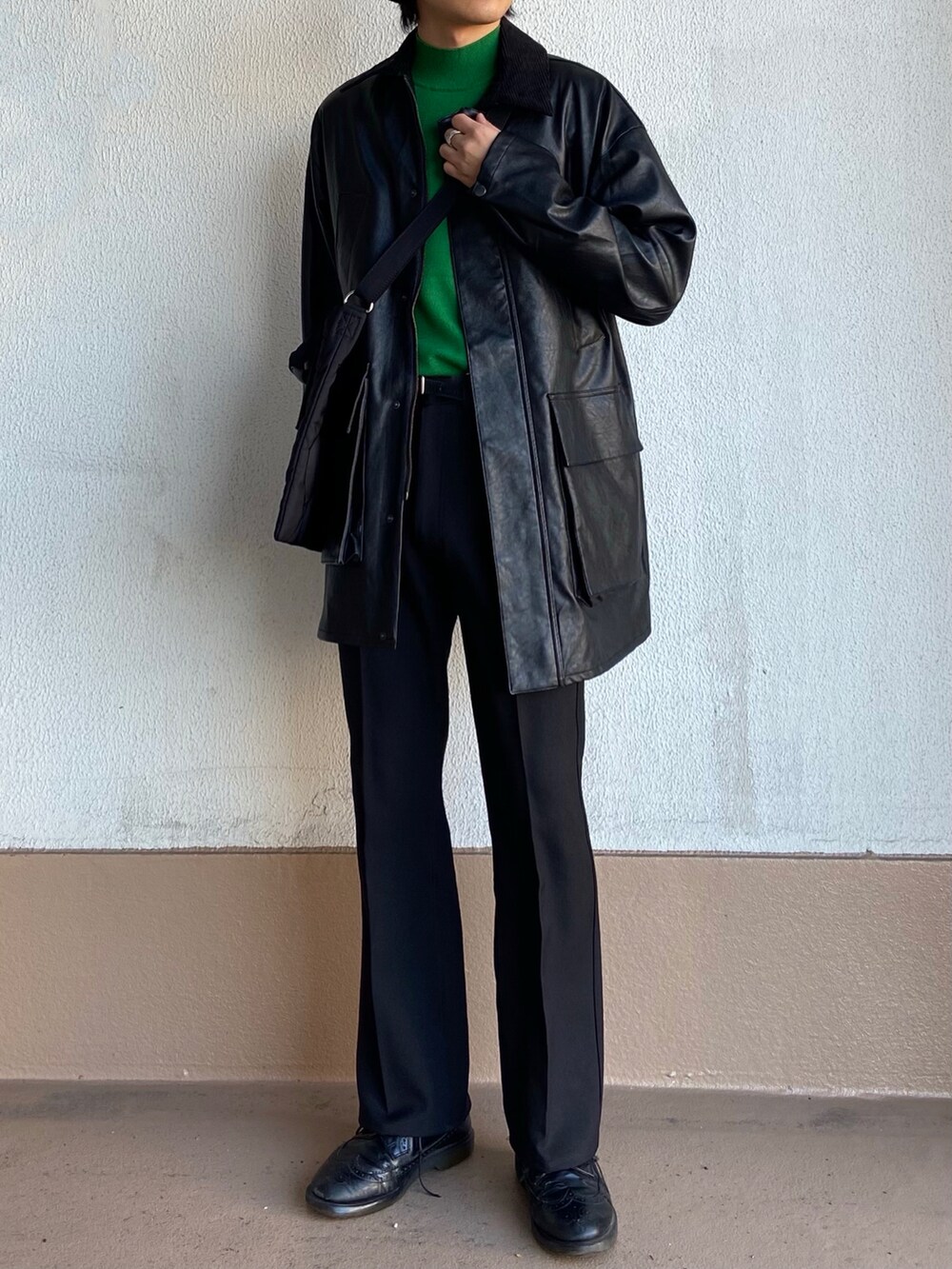 ブラック系のトートバッグ、グリーン系のニット/セーター、ブラック系のカバーオールを着用したメンズの冬コーディネートの2枚目の写真