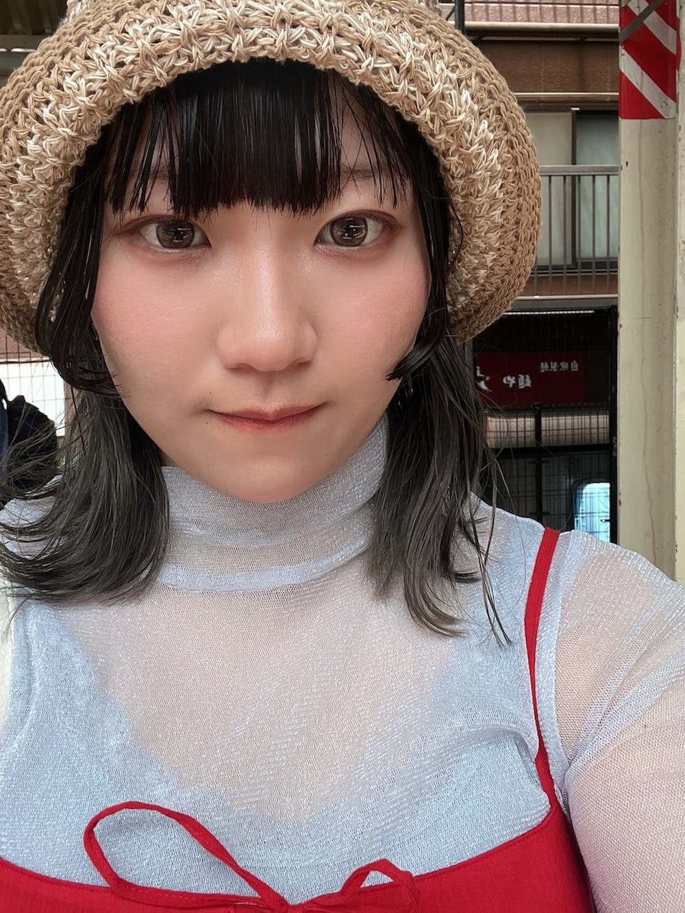 レッド系のトップス、グレー系のパンツ、ホワイト系のバッグを着用したレディースの春コーディネートの2枚目の写真