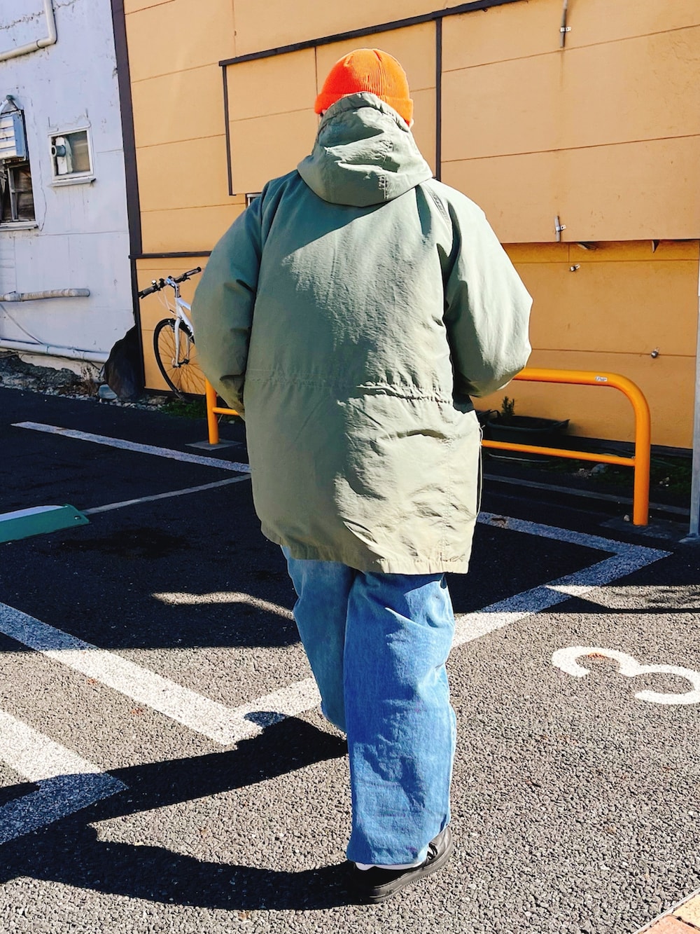 グリーン系のマウンテンパーカー、ブルー系のデニムパンツ、ブラック系のスニーカーを着用したメンズの冬コーディネートの2枚目の写真