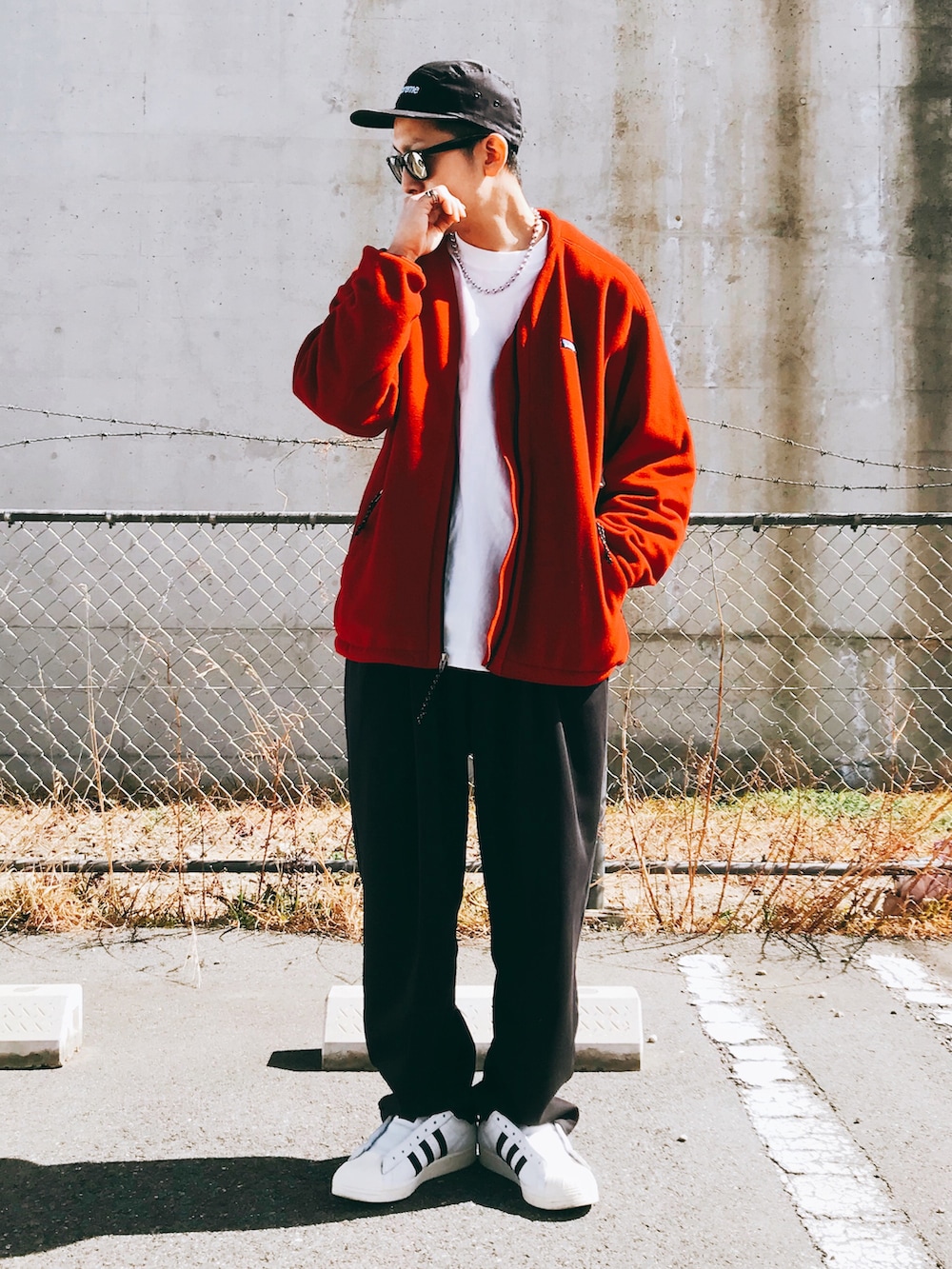 レッド系のジャケット/アウター、ブラック系のパンツ、ホワイト系のスニーカーを着用したメンズの春コーディネートの2枚目の写真