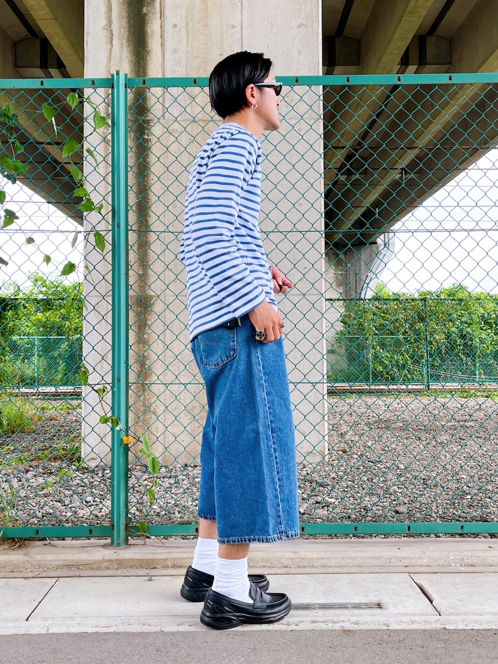 ブルー系のデニムパンツ、ホワイト系のTシャツ/カットソー、ブラック系のローファーを着用したメンズの夏コーディネートの4枚目の写真