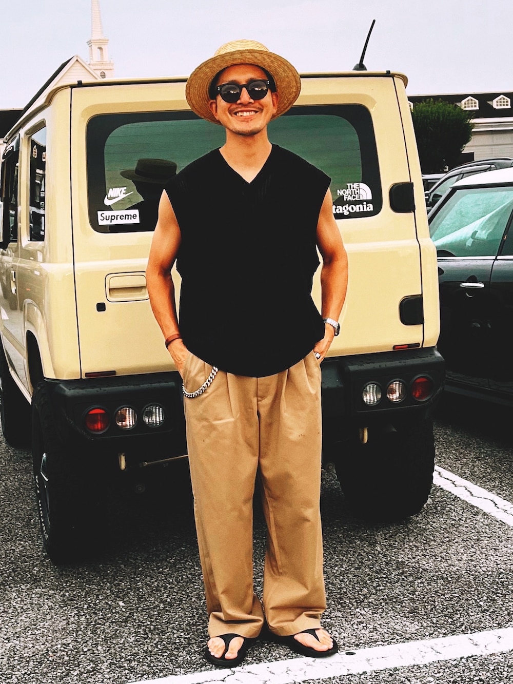 ブラック系のベスト、ベージュ系のチノパンツ、ブラック系のサンダルを着用したメンズの夏コーディネートの2枚目の写真