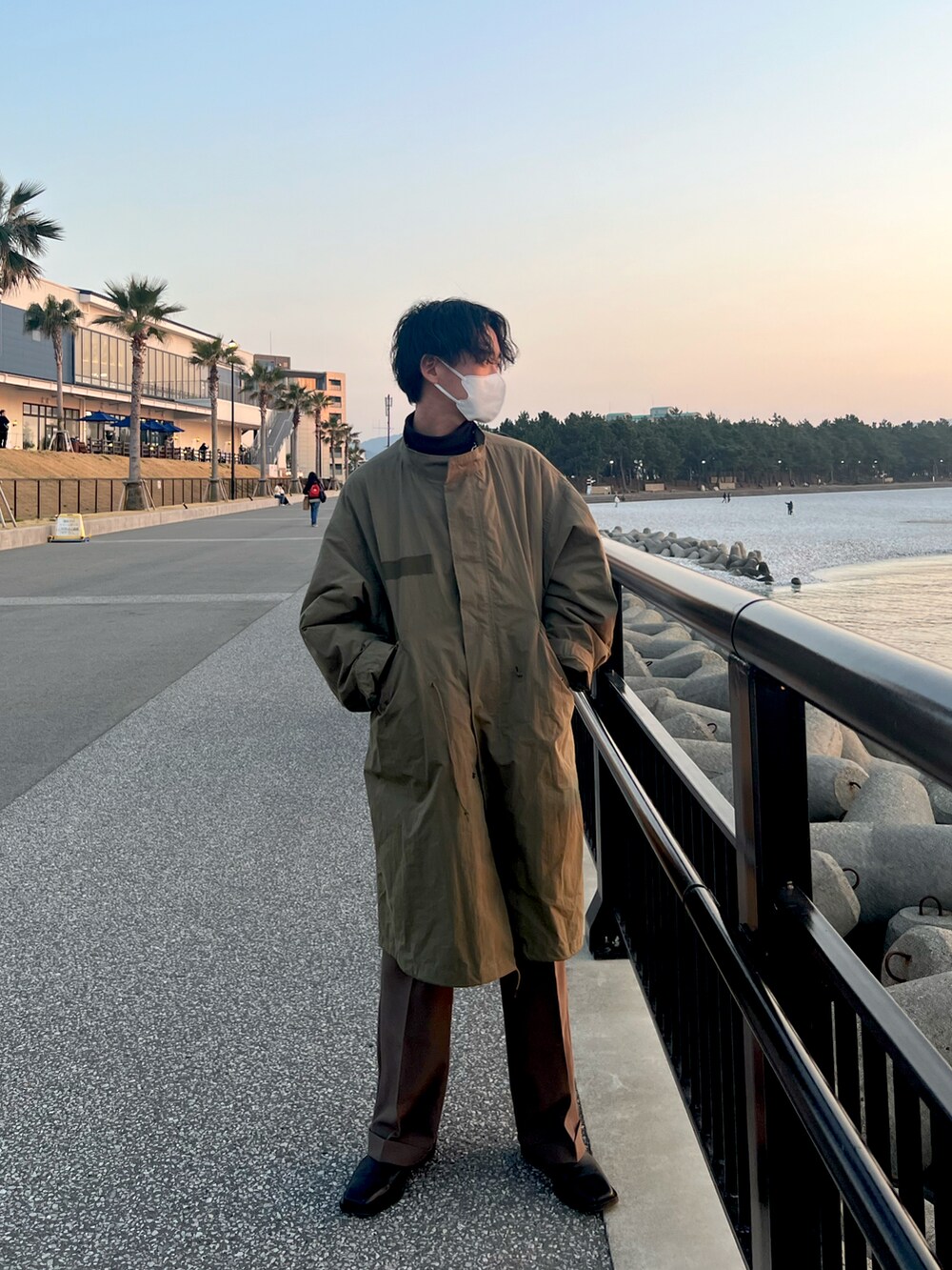 グリーン系のモッズコート、ブラウン系のスラックスを着用したメンズの春コーディネートの2枚目の写真