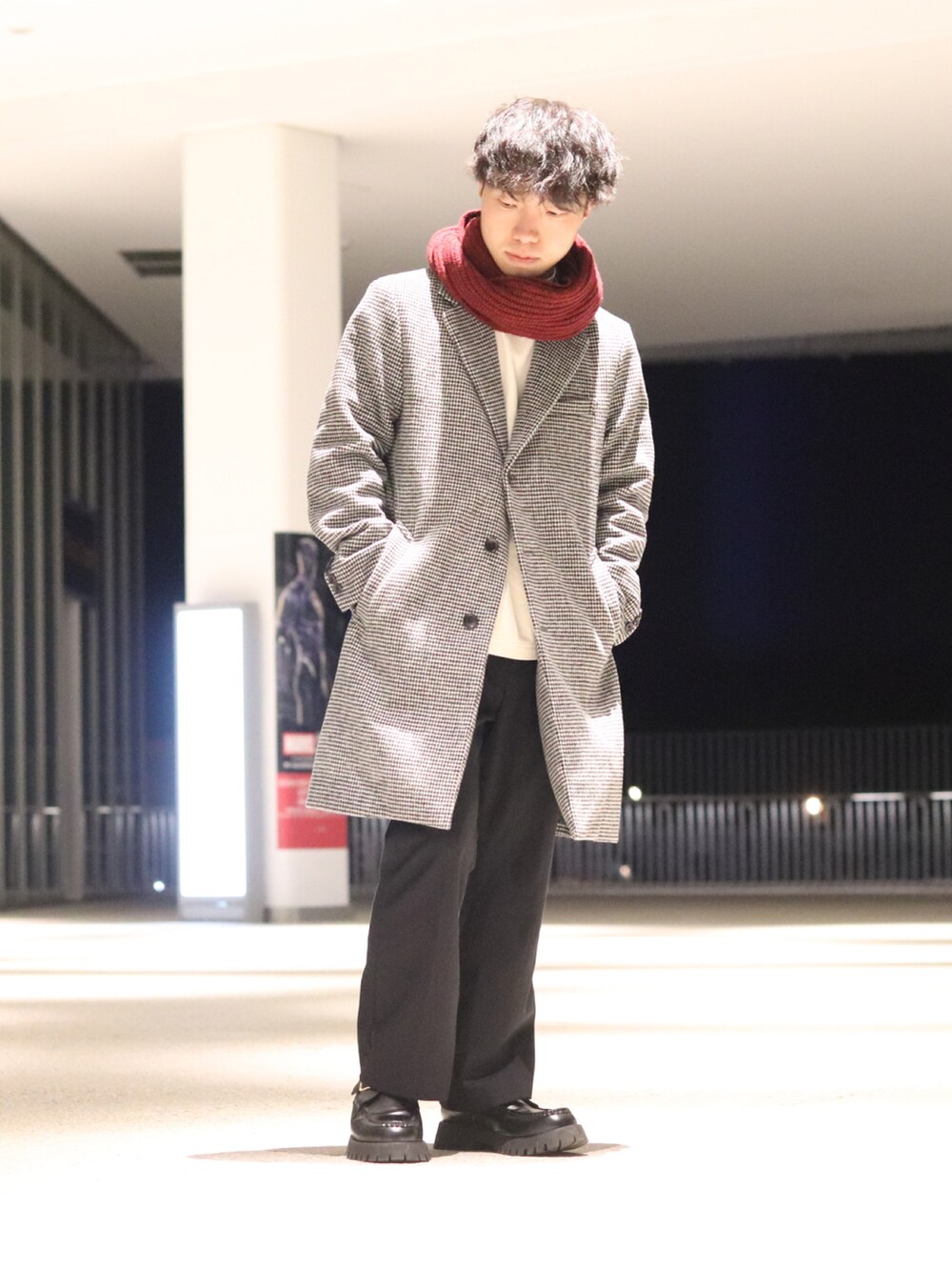 グレー系のチェスターコート、ブラック系のスラックス、ブラック系のローファーを着用したメンズの冬コーディネートの2枚目の写真