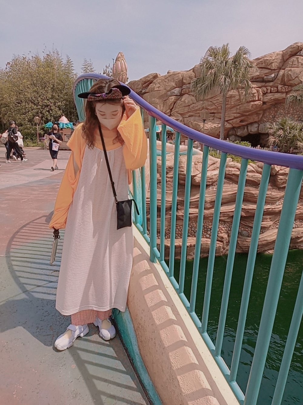 ホワイト系のワンピース、オレンジ系のトップス、ブラック系のショルダーバッグを着用したレディースの春コーディネートの3枚目の写真