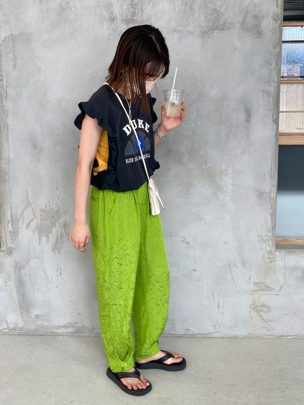 グリーン系のパンツ、ブラック系のトップスを着用したレディースの夏コーディネートの2枚目の写真