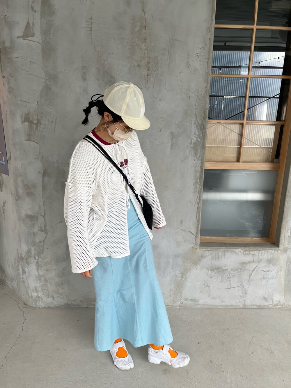 ホワイト系のカーディガン/ボレロ、ブルー系のスカート、ホワイト系のキャップを着用したレディースの春コーディネートの2枚目の写真