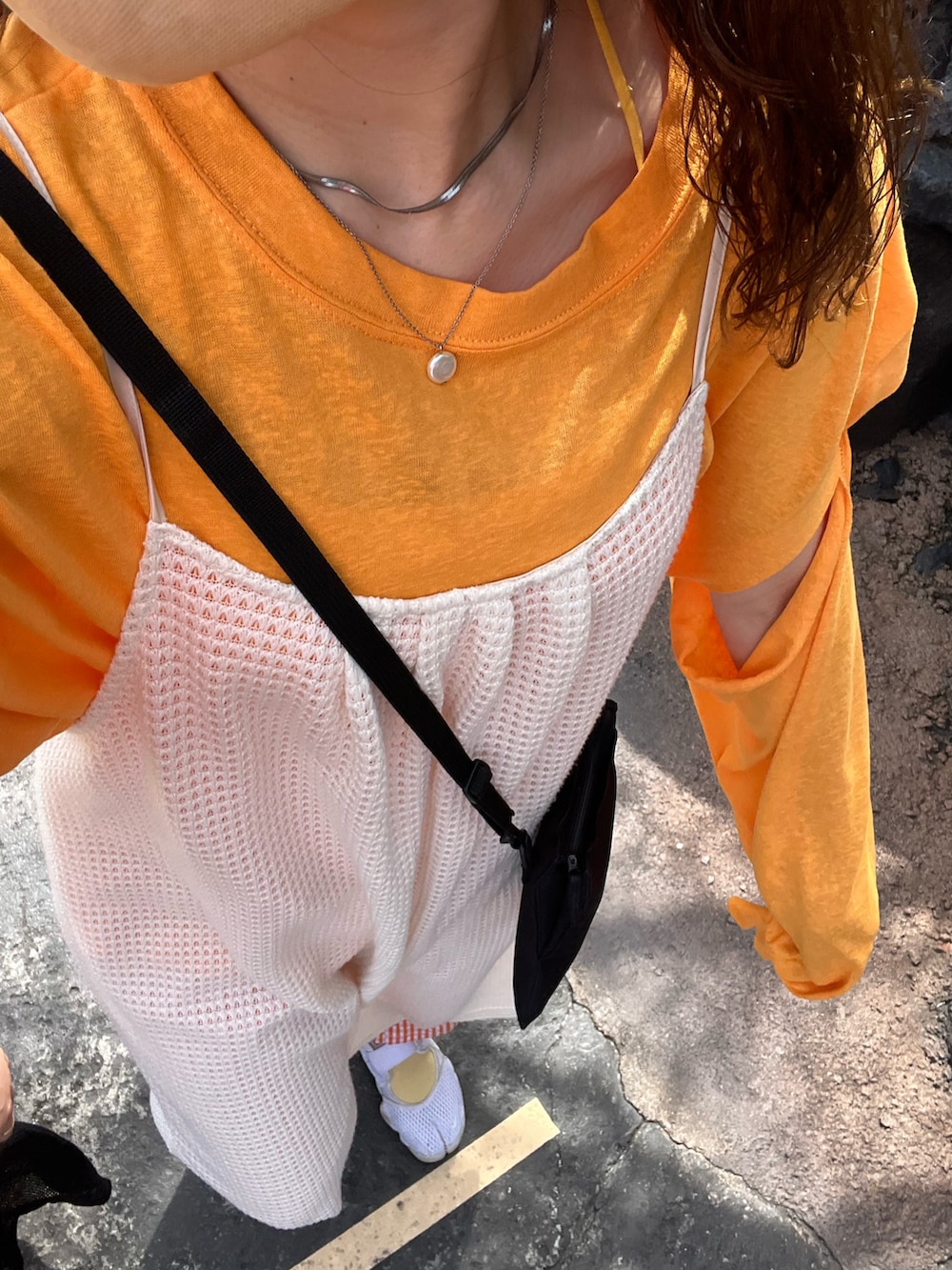 ホワイト系のワンピース、オレンジ系のトップス、ブラック系のショルダーバッグを着用したレディースの春コーディネートの2枚目の写真