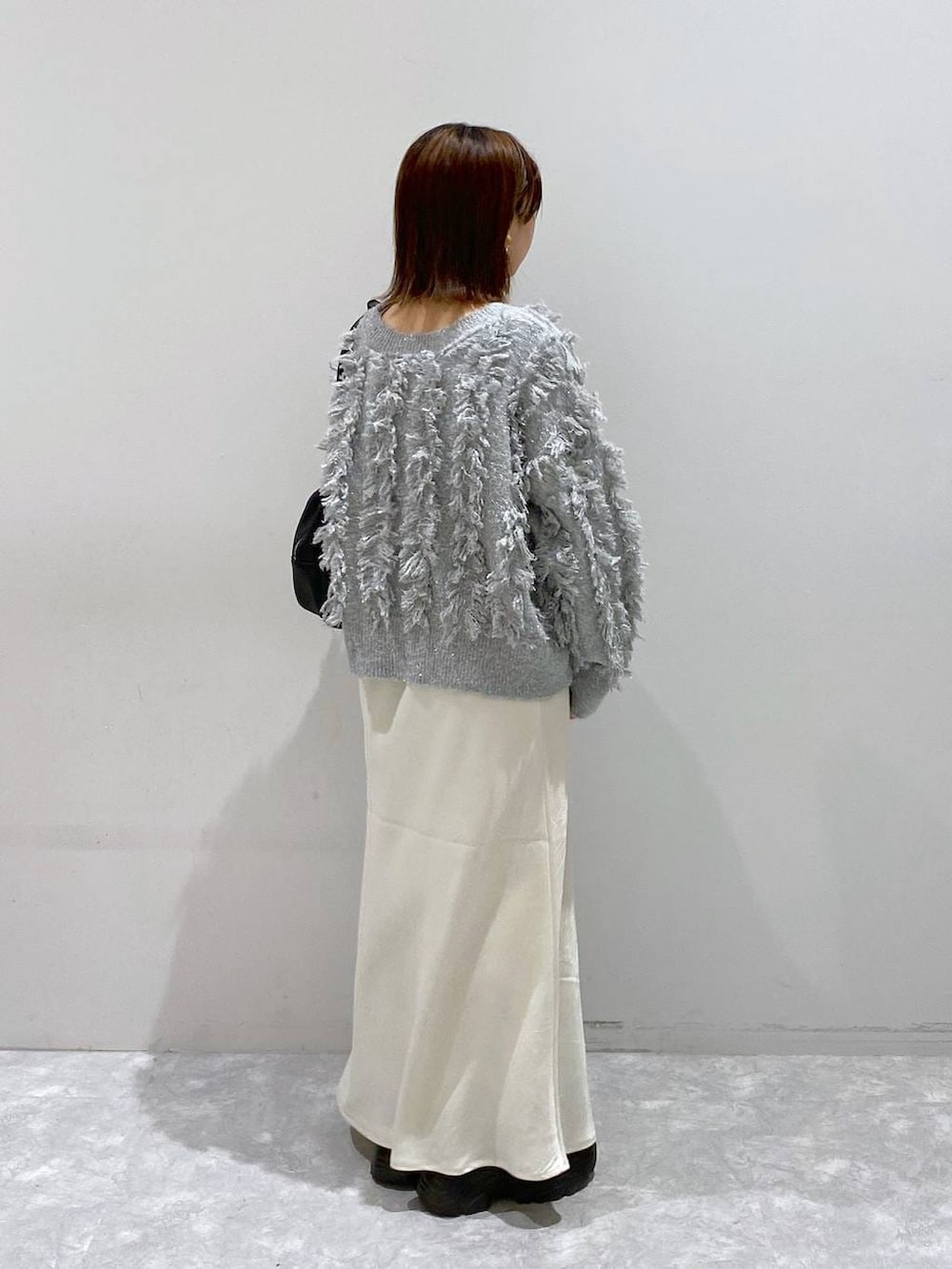 ブラック系のスニーカー、ホワイト系のスカート、グレー系のカーディガン/ボレロを着用したレディースの秋コーディネートの5枚目の写真