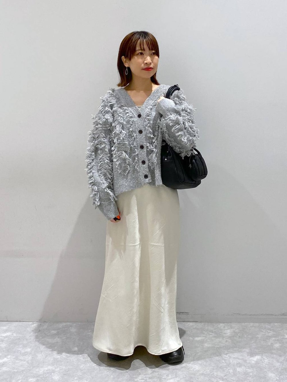 ブラック系のスニーカー、ホワイト系のスカート、グレー系のカーディガン/ボレロを着用したレディースの秋コーディネートの8枚目の写真