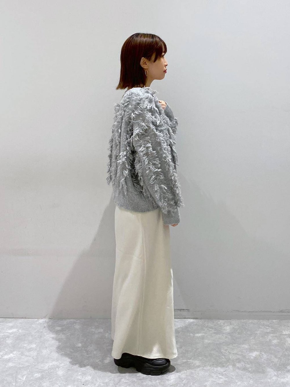 ブラック系のスニーカー、ホワイト系のスカート、グレー系のカーディガン/ボレロを着用したレディースの秋コーディネートの6枚目の写真