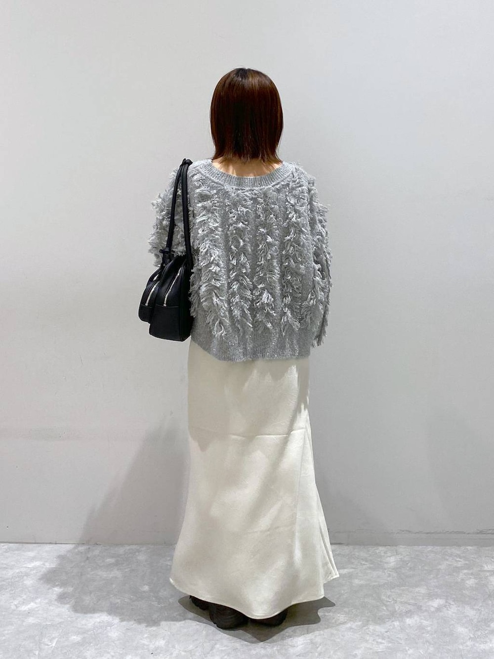 ブラック系のスニーカー、ホワイト系のスカート、グレー系のカーディガン/ボレロを着用したレディースの秋コーディネートの4枚目の写真