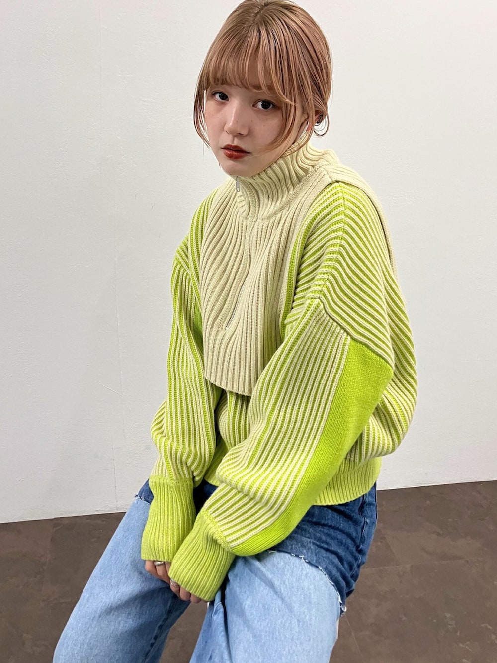 グリーン系のニット/セーター、ブルー系のデニムパンツを着用したレディースの夏コーディネートの3枚目の写真