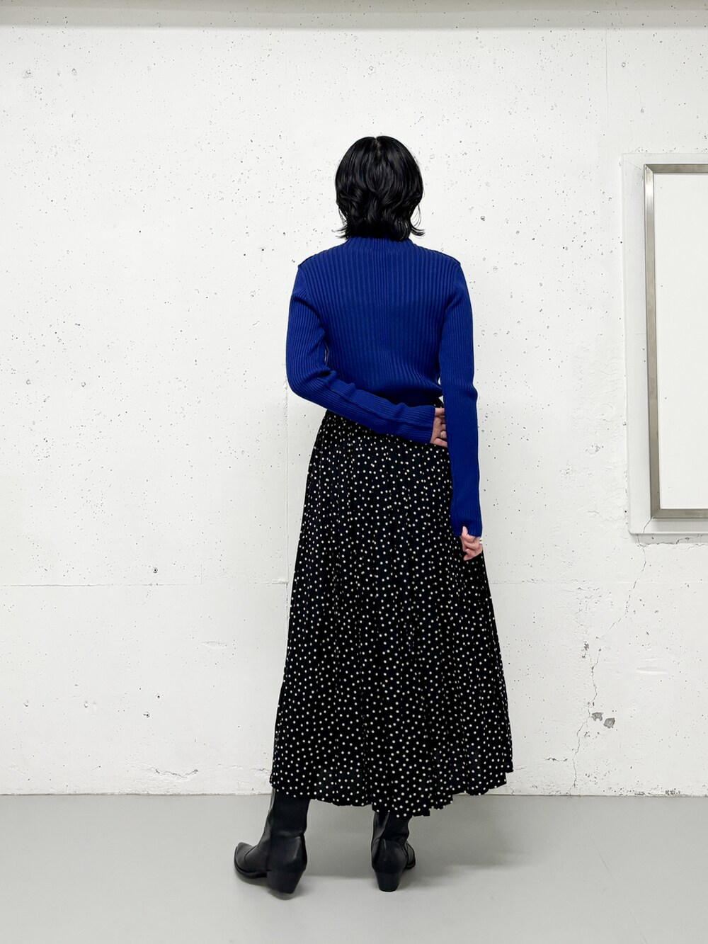 ブラック系のスカート、ブルー系のニット/セーター、ブラック系のブーツを着用したレディースの冬コーディネートの3枚目の写真