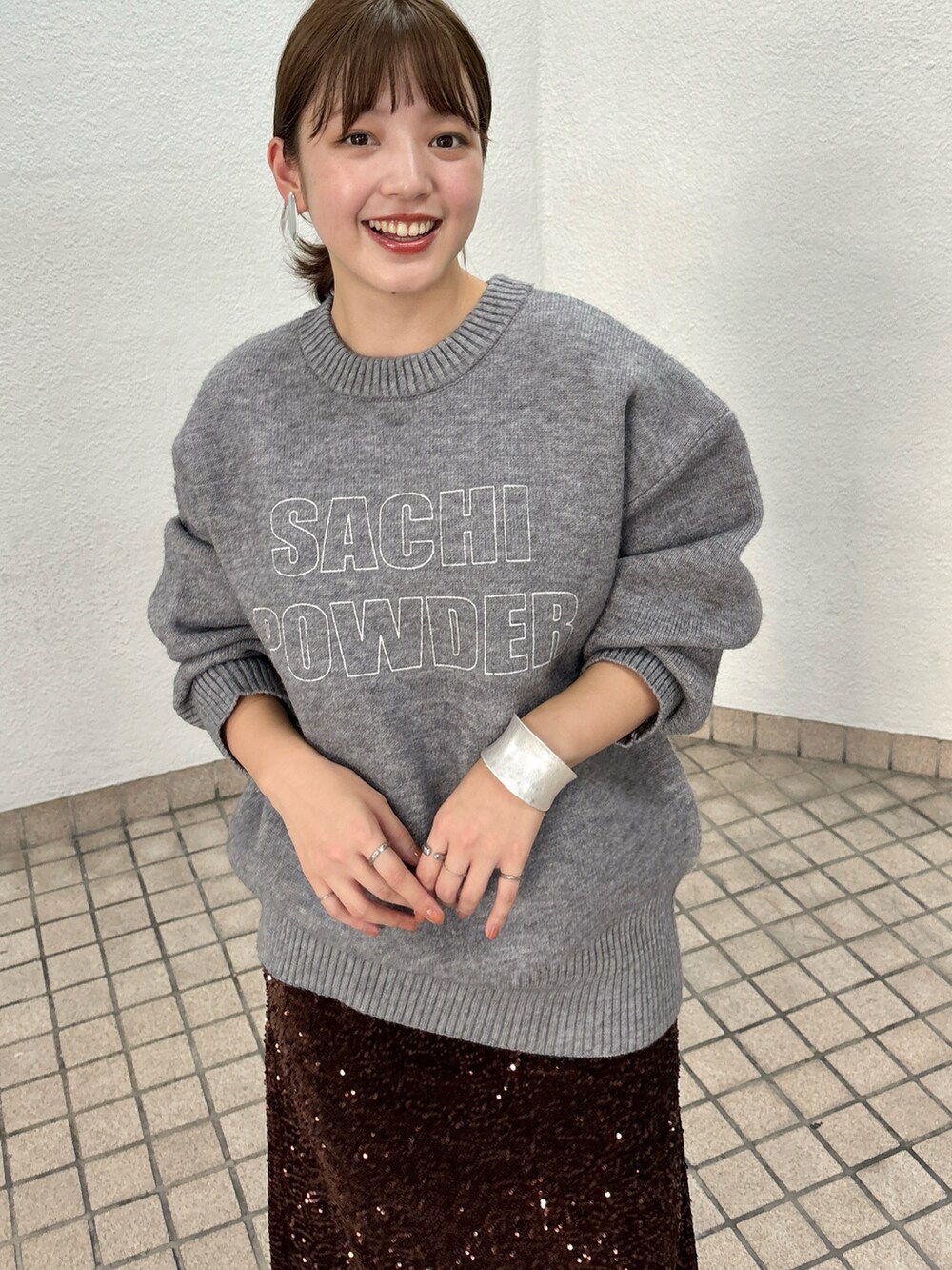 グレー系のニット/セーター、ブラウン系のスカート、ブラック系のブーツを着用したレディースの秋コーディネートの2枚目の写真