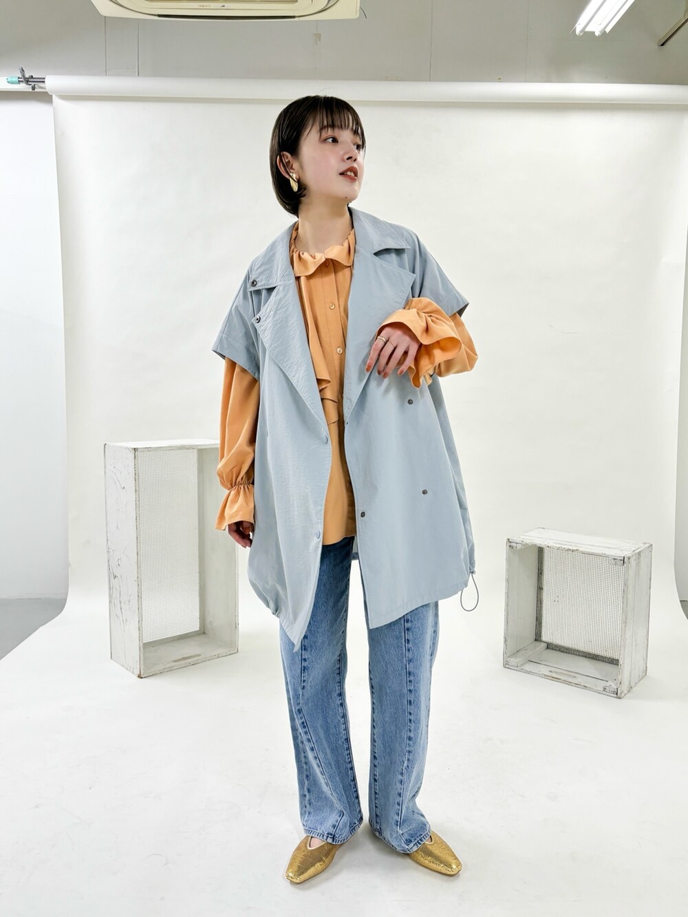 ブルー系のポンチョ、ブルー系のデニムパンツ、ゴールド系のパンプスを着用したレディースの冬コーディネートの3枚目の写真