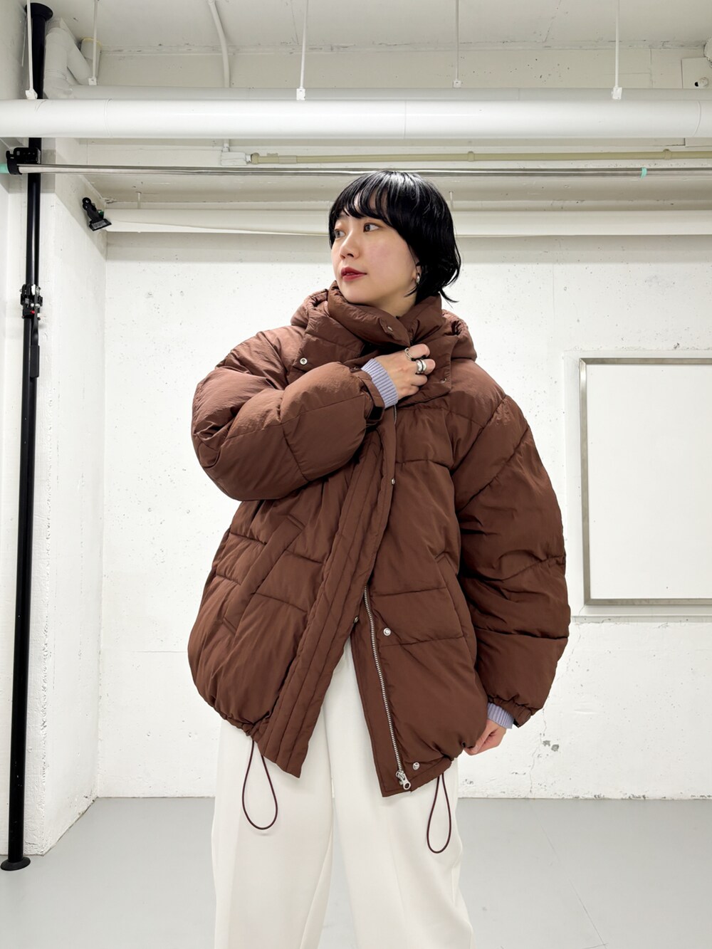 ブラウン系のダウンジャケット/コート、パープル系のニット/セーター、ホワイト系のその他パンツを着用したレディースの冬コーディネートの3枚目の写真