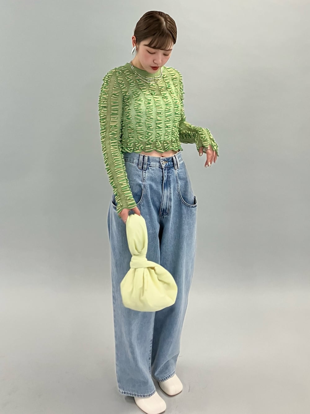 ブルー系のデニムパンツ、ホワイト系のブーツ、グリーン系のニット/セーターを着用したレディースの夏コーディネートの5枚目の写真