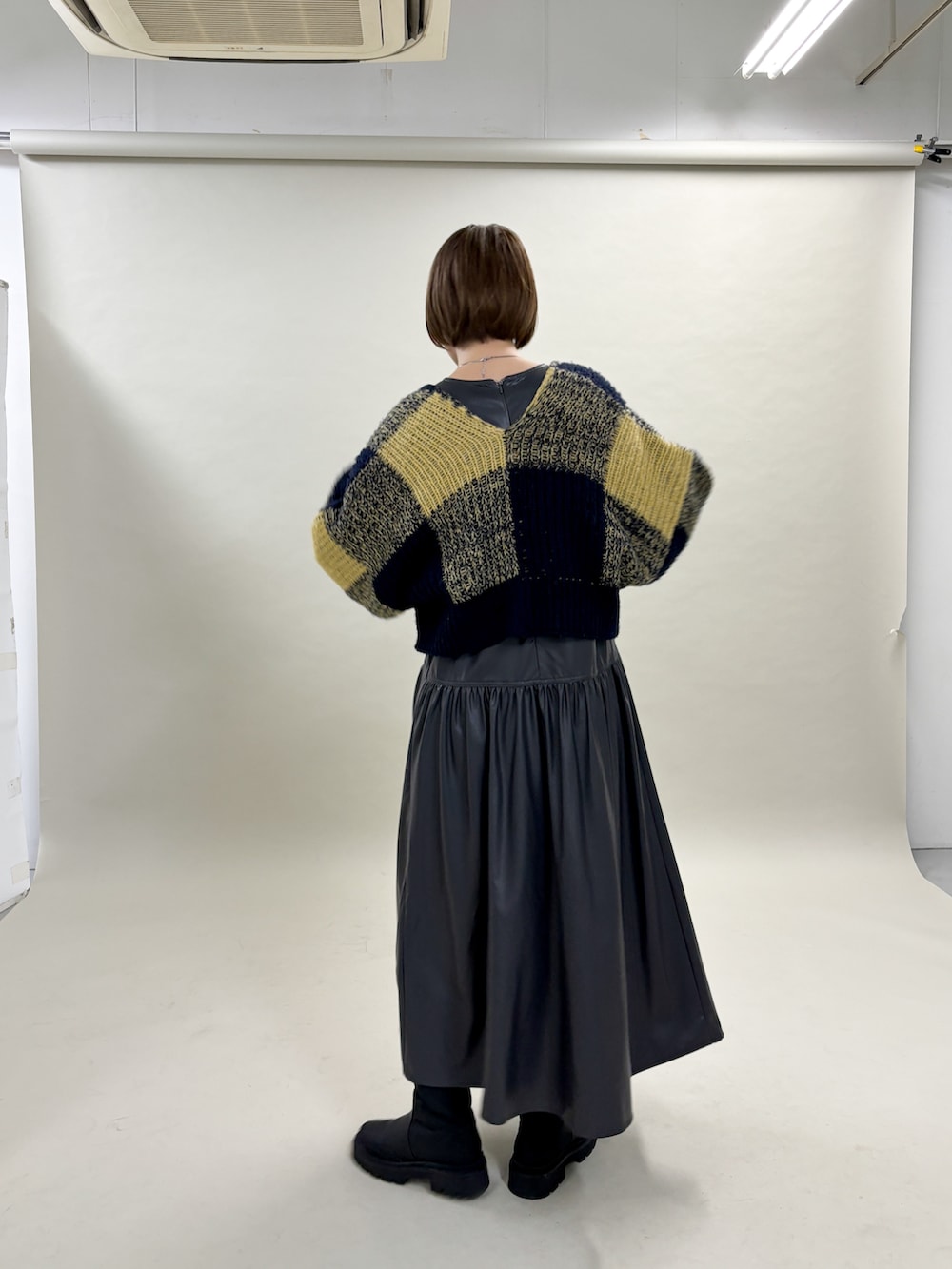 ブルー系のカーディガン/ボレロ、グレー系のワンピース、ブラック系のブーツを着用したレディースの冬コーディネートの2枚目の写真