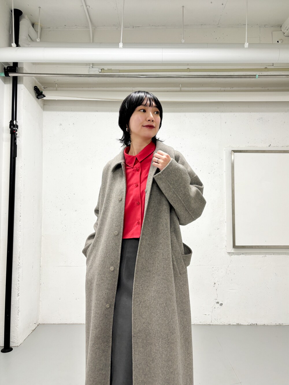 グレー系のステンカラーコート、ピンク系のシャツ/ブラウス、グレー系のスカートを着用したレディースの冬コーディネートの3枚目の写真