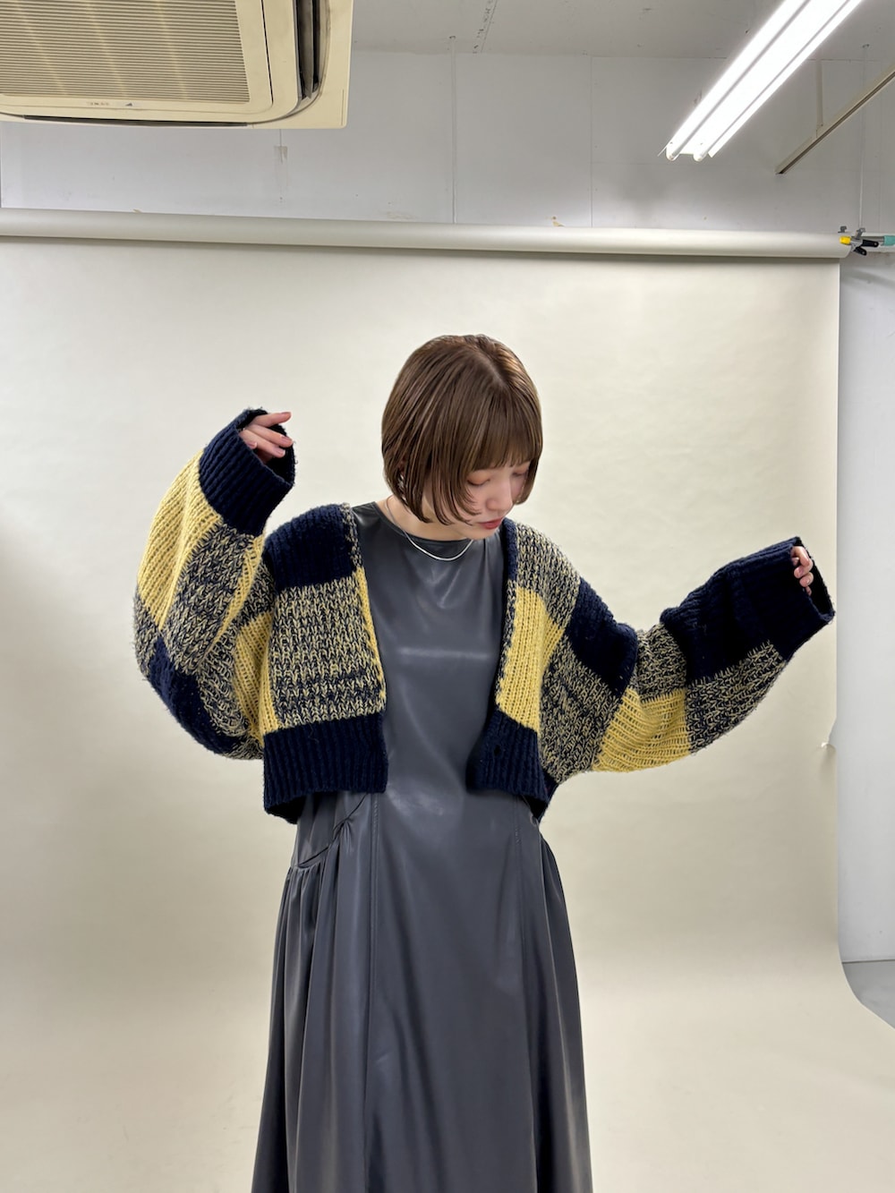 ブルー系のカーディガン/ボレロ、グレー系のワンピース、ブラック系のブーツを着用したレディースの冬コーディネートの3枚目の写真