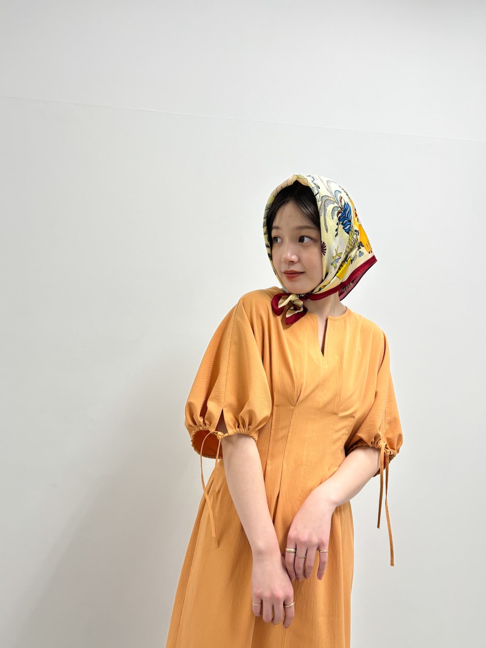 ベージュ系のその他シューズ、オレンジ系のワンピース、レッド系のバンダナ/スカーフを着用したレディースの春コーディネートの2枚目の写真