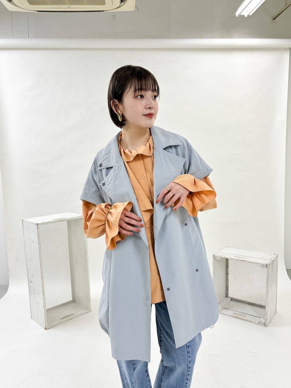 ブルー系のポンチョ、ブルー系のデニムパンツ、ゴールド系のパンプスを着用したレディースの冬コーディネートの4枚目の写真