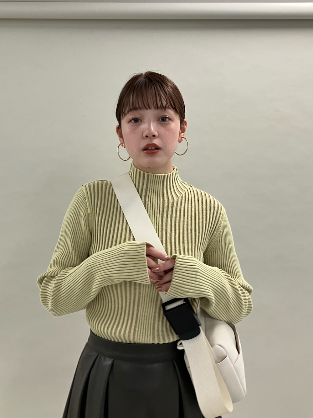 イエロー系のニット/セーター、ホワイト系のショルダーバッグ、ホワイト系のブーツを着用したレディースの夏コーディネートの3枚目の写真