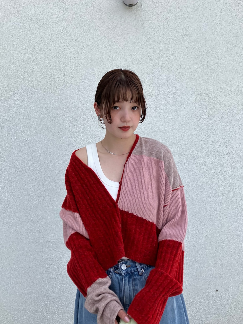 レッド系のニット/セーター、ブラック系のその他シューズ、ブルー系のデニムパンツを着用したレディースの夏コーディネートの3枚目の写真