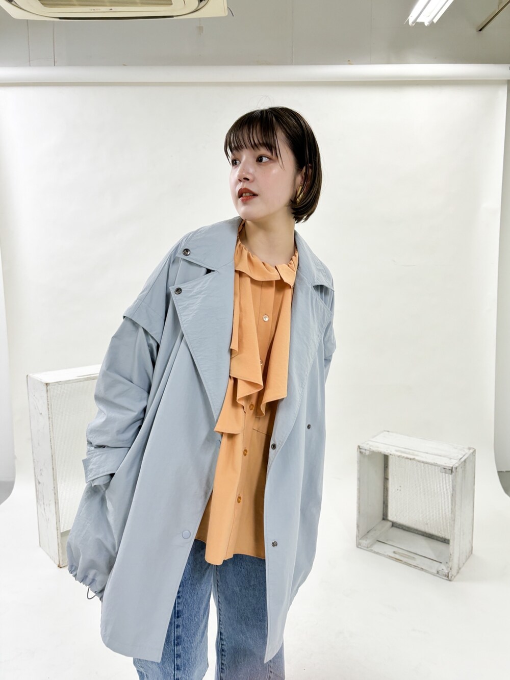 ブルー系のポンチョ、ブルー系のデニムパンツ、ゴールド系のパンプスを着用したレディースの冬コーディネートの2枚目の写真